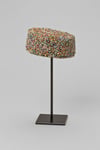 A decorative colorful cap displayed on a black metal stand