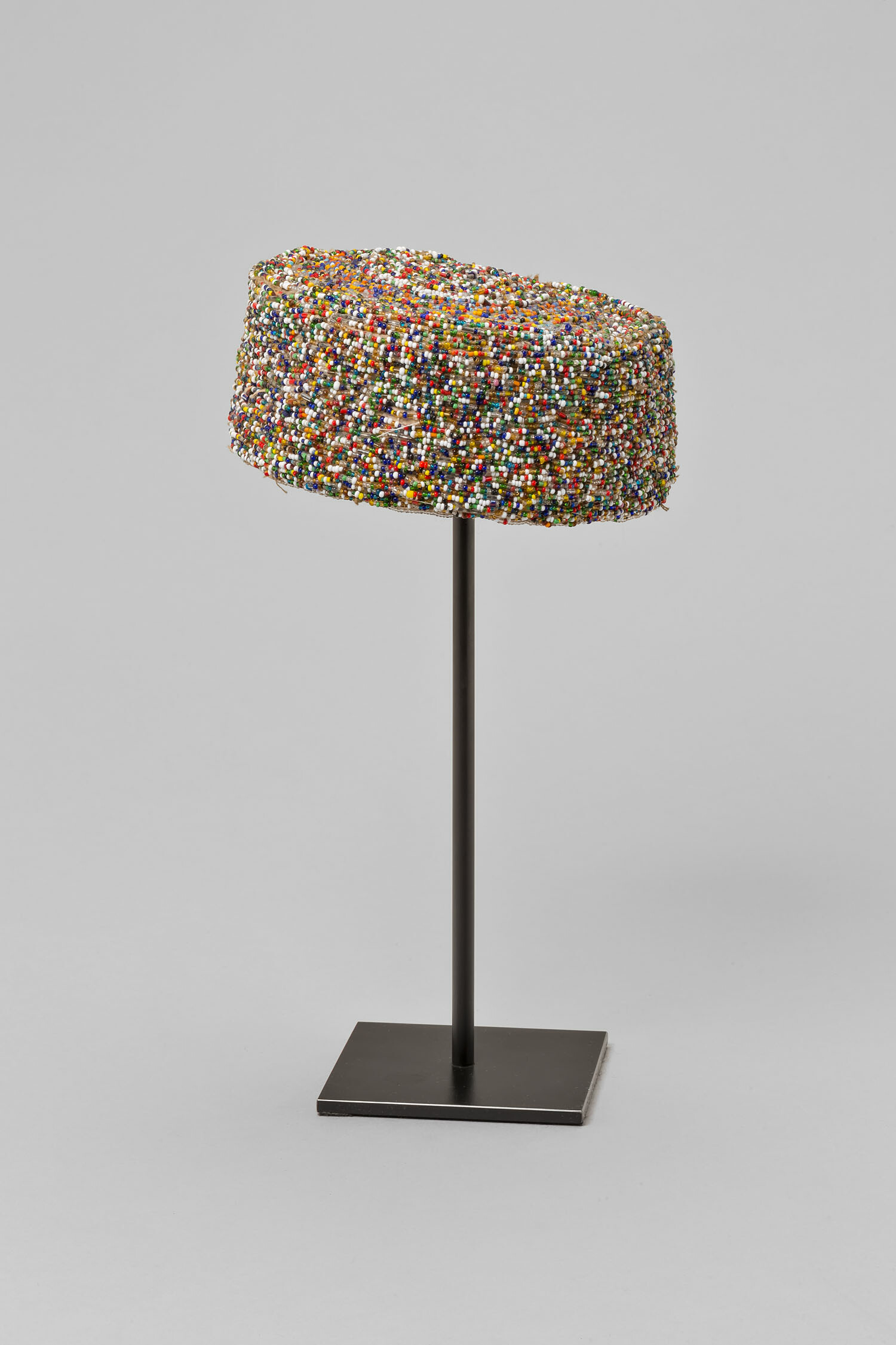 A decorative colorful cap displayed on a black metal stand