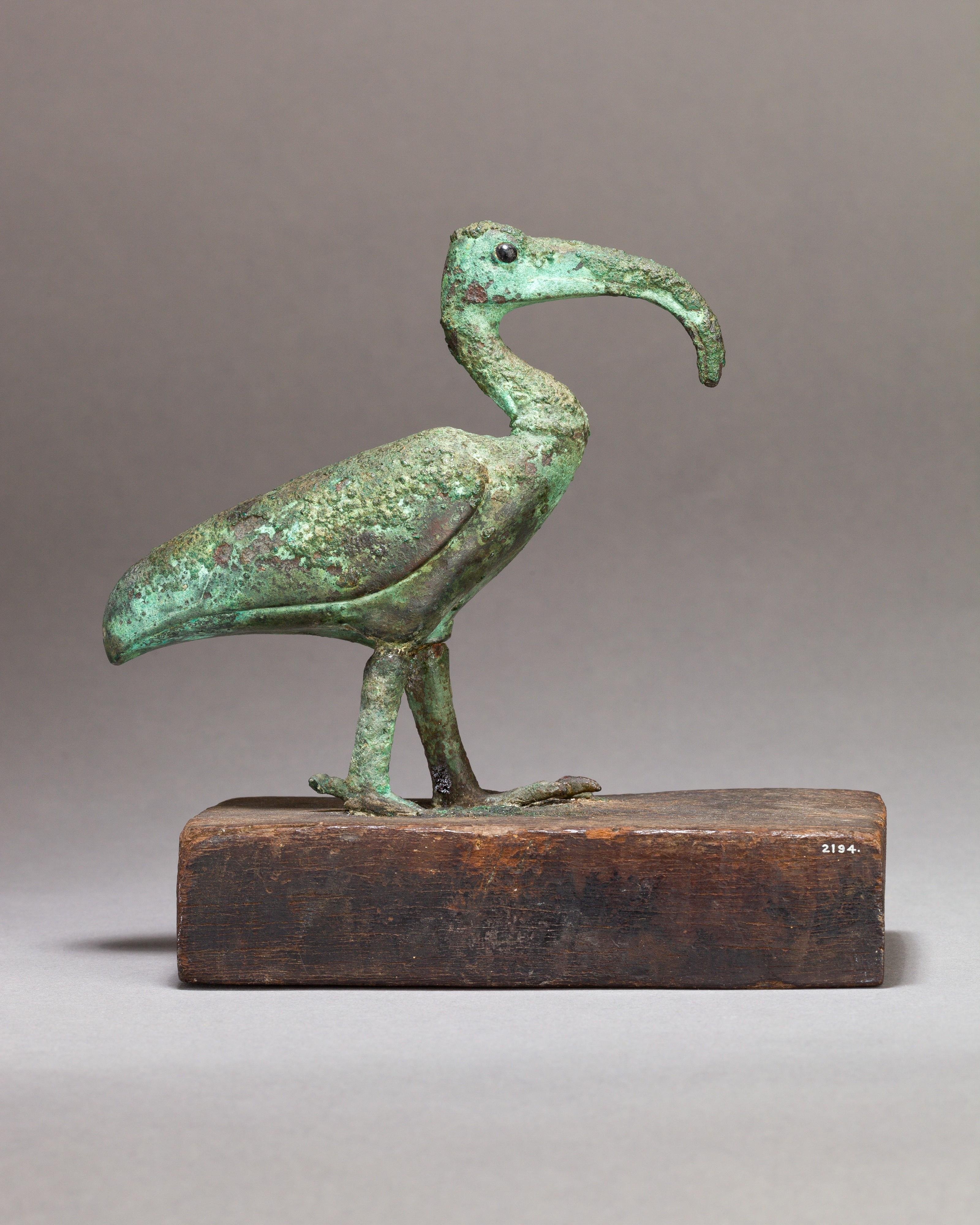 Metallfigur mit einem Vogel auf einem Holzsockel
